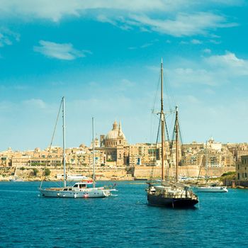 picturesque view of sailing boats with Valletta cityscape on the background, Malta