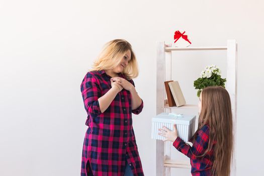 Young mother received a surprise from her daughter feeling excited open the mouth and looking at the gift in amazement in mother's day. Holidays, birthday and presents concept