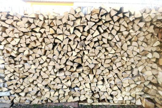 Natural background of evenly folded wooden logs prepared for storage in winter. Birch and aspen logs are exactly stacked on top of each other.