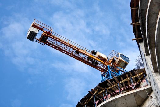 construction site with crane, building and blue cloudy sky in background