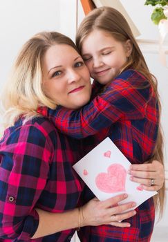 Mother's Day and family holidays - Mother reading greeting card from daughter.