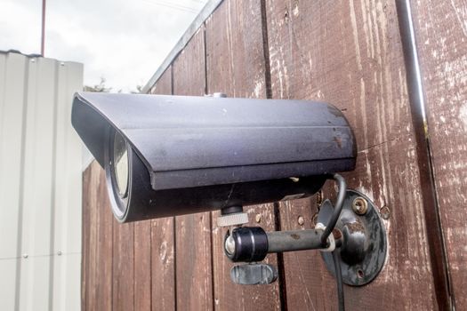 Attached to the fence is an old CCTV camera. The concept of home and family protection.