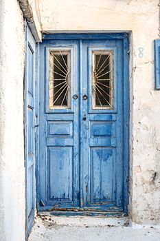 Old painted blue wooden door with cracked paint. Vintage blue door on the streets of Greece