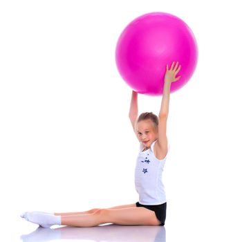 Beautiful little girl doing exercises on a big ball for fitness. The concept of sport and a healthy lifestyle. Isolated on white background.