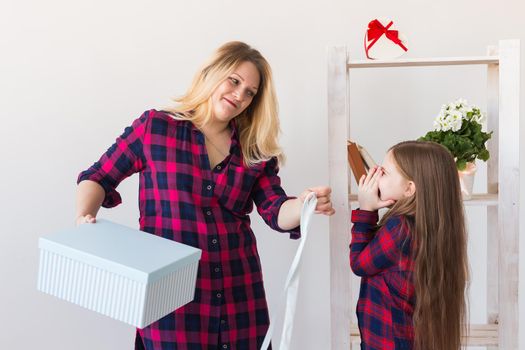 Young mother received a surprise from her daughter feeling excited open the mouth and looking at the gift in amazement in mother's day. Holidays, birthday and presents concept