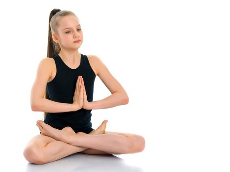 A nice little girl sits in a lotus position and meditates. Concept of yoga, happy people. Isolated on white background.