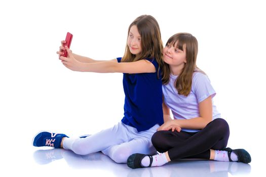Two happy smiling girls make a self-portrait on a smartphone. The concept of people and technology. Isolated on white background.