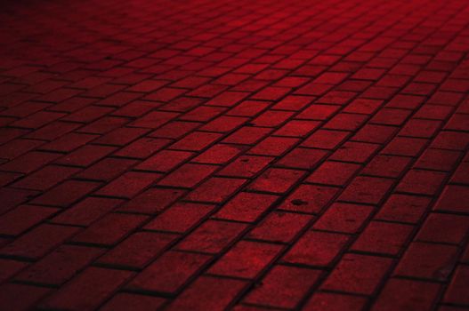 street road made of blocks and lit by red light from electric ad