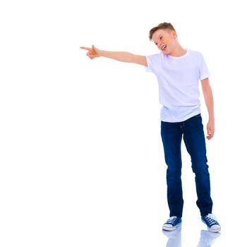 A handsome little school-age boy in a clean white T-shirt, on the surface of which you can make an inscription, points to something. The concept of advertising a variety of goods, printing on the surface of clothing. Isolated on white background.