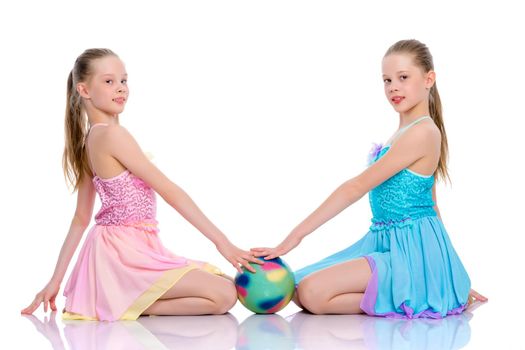 Two cheerful little girls gymnasts in competitions, perform exercises with the ball. The concept of children's sports, fitness, healthy lifestyle. Isolated on white background.