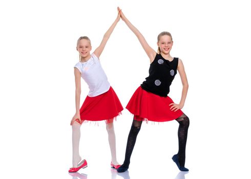 Two cheerful little girls are dancing in the studio on a white background. The concept of a children's dance school, happy people. Isolated.