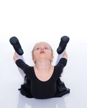 A sweet little gymnast girl performs an acrobatic element on the floor. The concept of sport, healthy lifestyle. Isolated on white background.