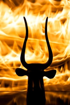 photo of the bull figurine with real flame background