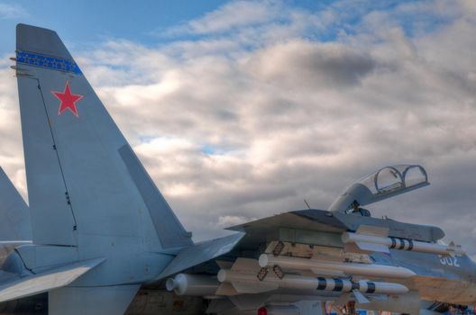 air fighter on the ground with opened cockpit, fully armed with missles with blue sky in background