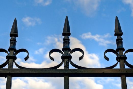 old beautiful metal fence with blue cloudy sky in background