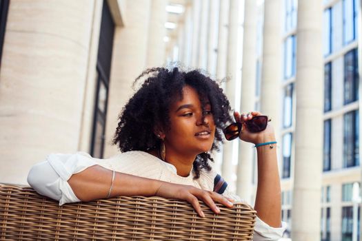 young pretty african girl posing cheerful on city background, lifestyle outdoor people concept close up