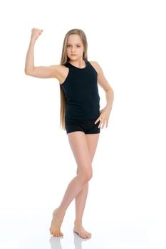 A beautiful girl gymnast of school age in a black T-shirt and shorts is preparing for the exercise. The concept of sport and fitness, happy people. Isolated on white background.