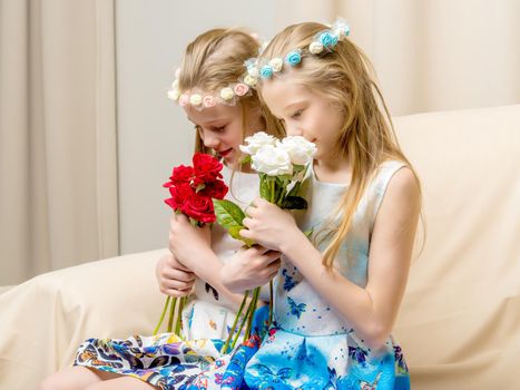 Two beautiful little girls with flowers in the studio. The concept of happy people, children.