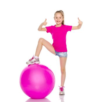 Beautiful little girl doing exercises on a big ball for fitness. The concept of sport and a healthy lifestyle. Isolated on white background.