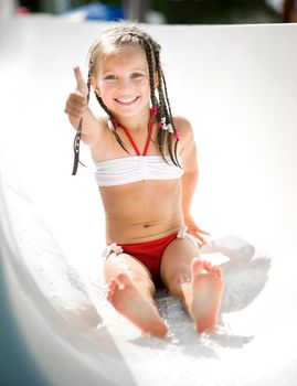 Little girl on water slide at aquapark show the thumb