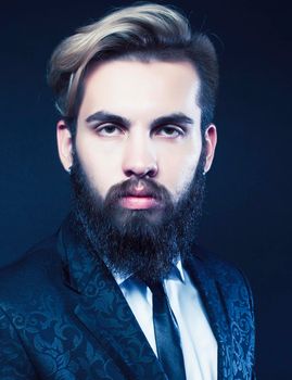 portrait of young bearded hipster guy on gray dark background close up, brutal modern man in suit, lifestyle people concept close up