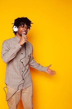 young handsome african american guy student posing cheerful and gesturing on yellow background, lifestyle people concept close up