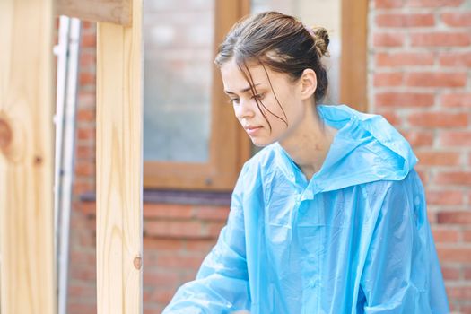 woman painter in protective clothing painting wood interior. High quality photo
