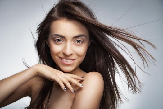 Portrait of attractive caucasian smiling woman with long hair on grey background.Looking at camera