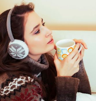 young pretty woman sitting in comfortable chair with coffee and blanket, winter season lifestyle people concept close up