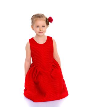 Beautiful little girl is sitting on the floor in the studio. The concept of a happy childhood, beauty and fashion. Isolated on white background.