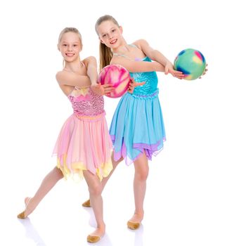 Two cheerful little girls gymnasts in competitions, perform exercises with the ball. The concept of children's sports, fitness, healthy lifestyle. Isolated on white background.