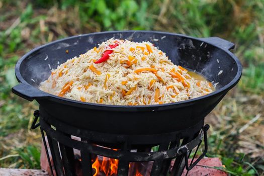 Cooking rice pilaf in a large cast-iron pot on fire