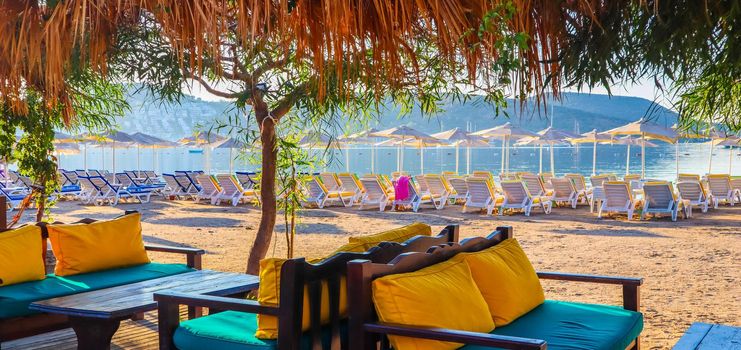 Beautiful beach on the shores of the calm blue bay of the Aegean Sea at sunset. Beach vacation and holiday destination concept. Bitez, Bodrum, Turkey