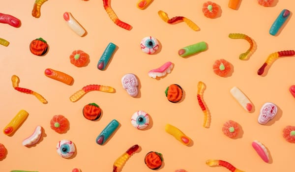 Halloween concept. Colorful sweets for Halloween party on orange background, top view flat lay