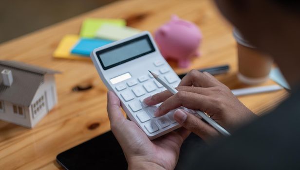 Man calculating financial chart for investment to buying property with house model. Money Saving Concept.