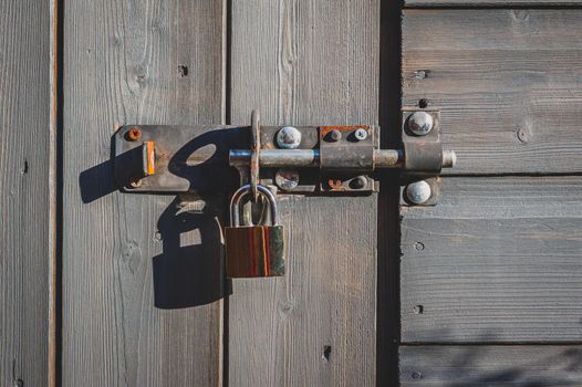 Brass padlock with bolt lock on wooden door.