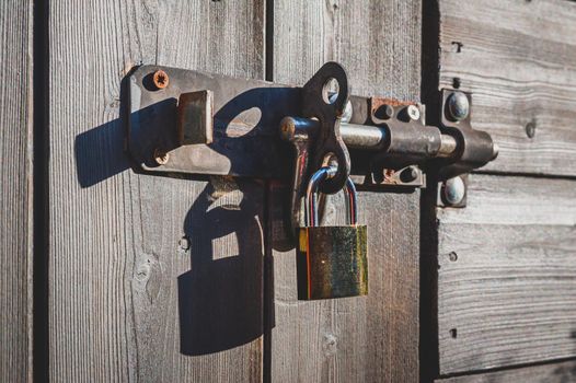 Brass padlock with bolt lock on wooden door.