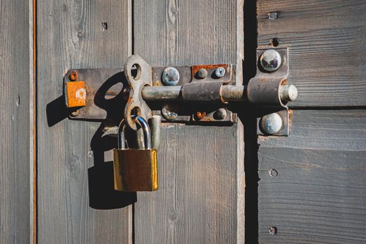 Brass padlock with bolt lock on wooden door.