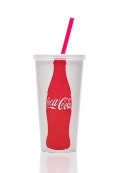 IRIVNE, CALIFORNIA - 11 JUN 2021: A Coca-Cola paper cup with red straw on white with reflection.