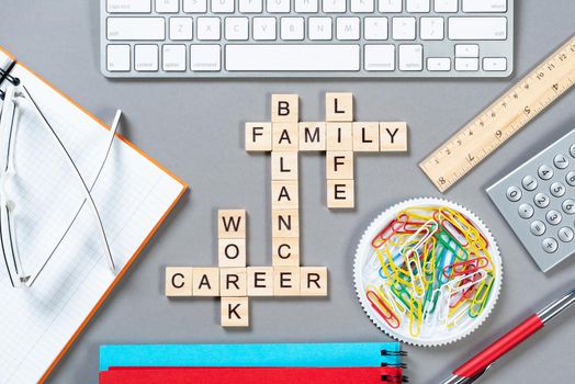 Business motivation concept with words from cubes. Still life of office workplace with crossword. Flat lay grey surface with computer keyboard and stationery. Strategy planning and business analytics.