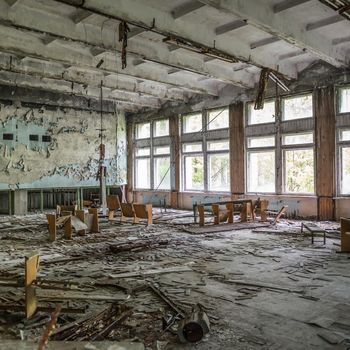 ruined assembly hall with debris and overturned chairs in abandoned Pripyat school