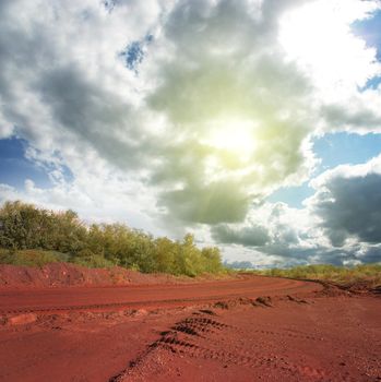 landscape with road on red ground and cloudy sky in Krivyi Rih, Ukraine