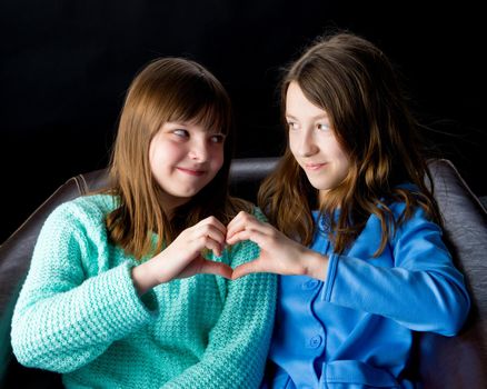 Two school girls folded their hands in the shape of a heart. Concept of friendship, happy people.