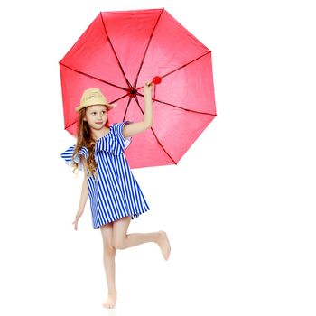 A stylish little girl with long blond hair in a very short, striped, summer blue dress and a straw hat.She is sheltered from the sun or rain under a red umbrella.Isolated on white background.