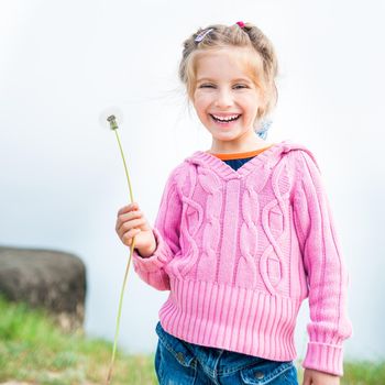 6-year-old beautiful girl holds in her hand dandelion