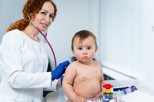 Pediatrician doctor concept. Children medical care. One year old baby girl examined by female pediatrician in clinic office. Child visiting doctor for health check-up. Doctor examine little patient.