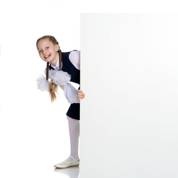 A nice little girl is looking because of an empty banner in which you can insert any text. The concept of a happy childhood, advertising, selling goods. Isolated on white background.