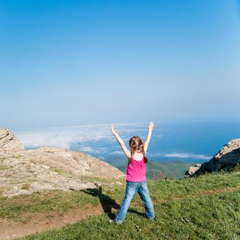 happy little girl on top of a mountain