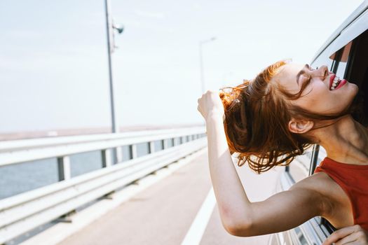cheerful woman peeking out of the car window trip road travel. High quality photo