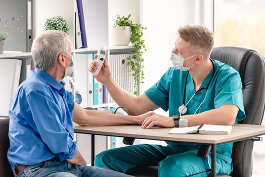 Doctor showing temperature on contactless thermometer screen to patient during appointment in clinic